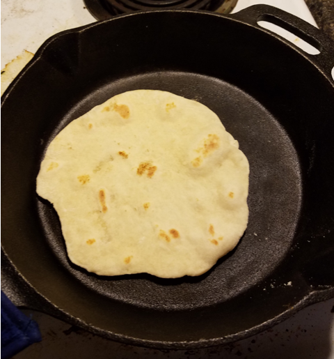 Homemade tortilla frying in a cast iron pan 